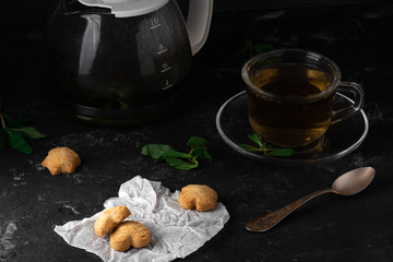 Fresh Homemade Cookies with Mint Tea and One Partly Eaten on Dark Stone Table with Copy Space Horizontal
