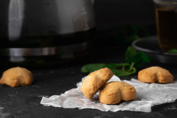 Tea with mint leaf with homemade coockies with ginger for Breakfast on the white backing paper and on the dark stone table background. Close-up, macro