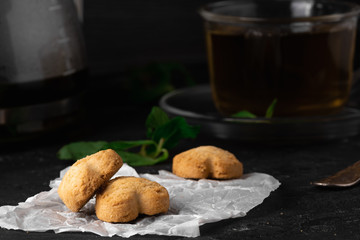Tea with mint leaf with homemade coockies with ginger for Breakfast on the white backing paper and on the dark stone table background. Close-up, macro