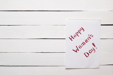 Congratulary text on a sheet of paper on the white background. Copy space on the left. Women's day concept. 