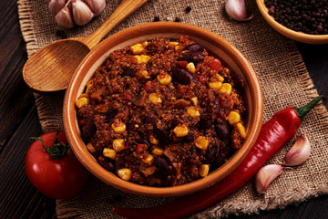 Mexican quinoa warm salad, chili, vegetarian food on dark wood background.
