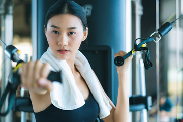 beautiful asian sport woman workout with weight machine to exercise in fitness beautiful woman lifts heavy dumbbell while training in the fitness Sports concept bodu builder  healthy lifestyle