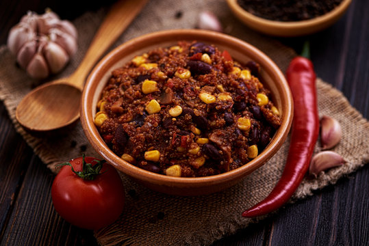 Mexican quinoa warm salad, chili, vegetarian food on dark wood background.