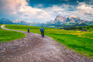 Carefree couple riding mountain bike on the alpine trail, Italy