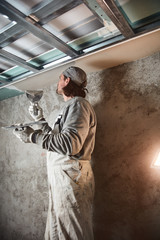 Workman plastering gypsum walls inside the house.