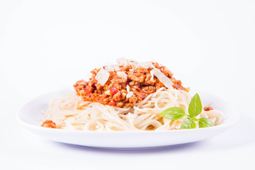 Spaghetti bolognese on a plate decorated with parmesan  cheese and fresh basil in a white background