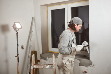 Workman plastering gypsum walls inside the house.