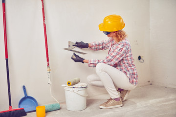 Working woman plastering / painting walls inside the house.