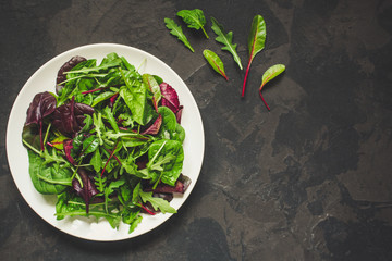 mix lettuce leaves salad in a plate (fresh green snack). food background. top