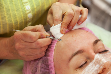 A young girl is lying on a couch during cosmetic procedures with a mask on the face above which...