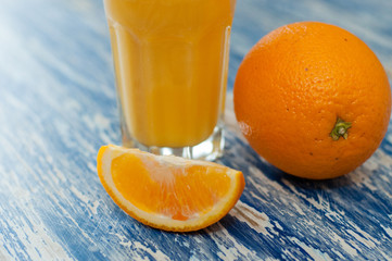 Glass of orange juice, whole orange and orange slice on sea blue background