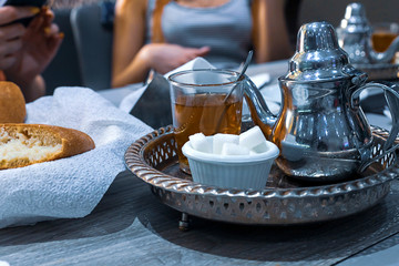 Moroccan tea with mint and sugar in a glasses on a copper plate with kettle