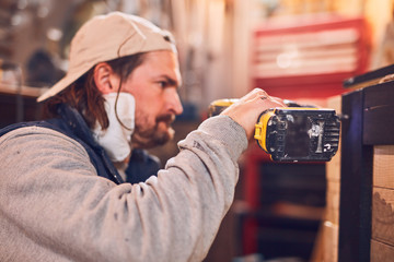 Male carpenter working on old wood in a retro vintage workshop.