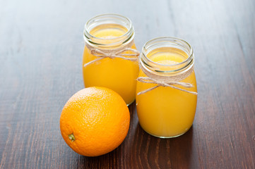 Fototapeta na wymiar Orange juice in jars and whole fruit rustic style