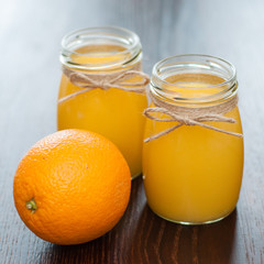 Fototapeta na wymiar Orange juice in jars and whole fruit rustic style