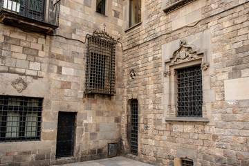 Fototapeta na wymiar Windows in a facade of an old Medieval building in the Gothic Quarter (Barrio Gotico) in Barcelona, Spain