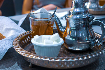 Moroccan tea with mint and sugar in a glasses on a copper plate with kettle