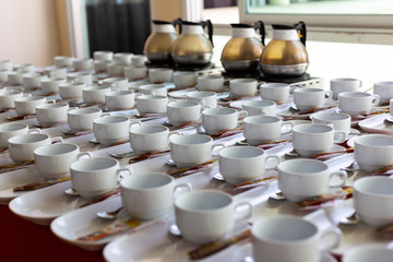 Group of empty ceramic white cup and saucer serving tea or coffee in Hotel setting