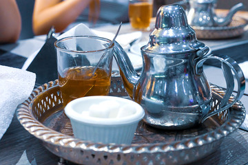 Moroccan tea with mint and sugar in a glasses on a copper plate with kettle