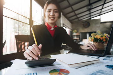 Close up Business woman using calculator and laptop for do math finance on wooden desk in office...