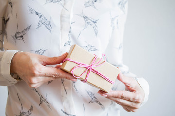 Female hands holding a small gift wrapped with pink ribbon. Selective focus,Selective focus, happy birthday