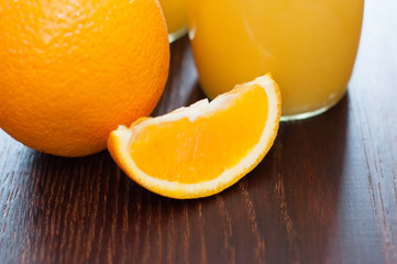 Orange slice and juice on a dark wooden table, rustic style side view, copy space