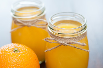 Orange and juice in jars on a dark wooden table, rustic style side view, copy space
