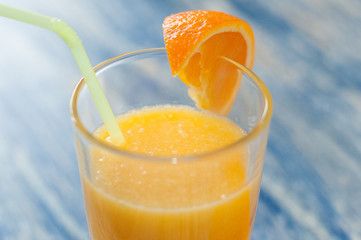 Alcoholic cocktail of fresh orange juice on a blue wooden background, copy space, closeup