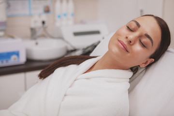 Charming beautiful young woman relaxing at cosmetology clinic after skincare treatment. Attractive female patient with perfect healthy glowing skin resting at beauty salon, copy space