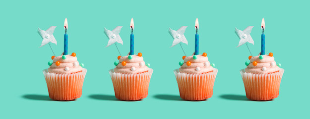 Tasty celebratory cupcakes with decorative lit candles