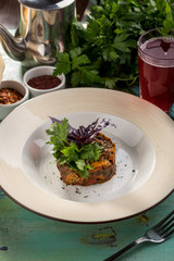 Baked eggplant with basil on top and glass of berry drink on blue wooden table