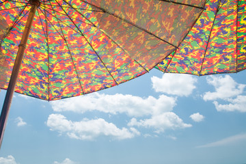 Striped beach umbrella on the beach (Cloudy sky background)