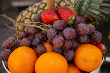 Fruit basket with red strawberries, grapes, pineapple, oranges. Fruit with high nutritional value, ready to be sold on the market or to be consumed directly at the table at lunch.