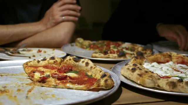 Authentic gourmet pizza selection served on restaurant table for sharing between friends during night out. Fresh ingridients and crispy crust on italian traditional plate