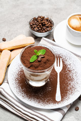 Classic tiramisu dessert in a glass and cup of coffee on concrete background