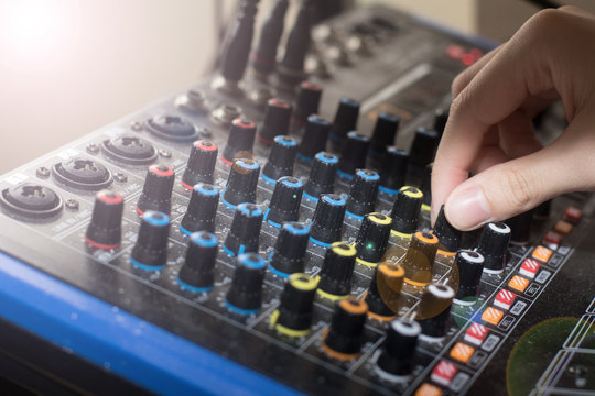 Recording engineer’s hand adjusts volume on audio sound board, Turning a dial on a mixing board