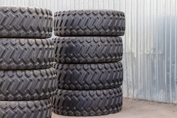 Large rubber tires for trucks lying on the street. Many new tires close-up with a large tread are on the ground.