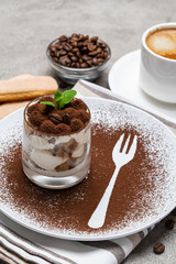 Classic tiramisu dessert in a glass and cup of coffee on concrete background
