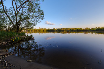 beautiful sunset by the river under tree leaves and branches. calm water
