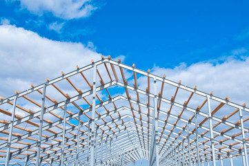 Metal frame of the new building against the blue sky with clouds. Metal frame of the building for...