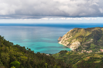 Coastal landscape with mountains and valleys on a spring day. View over the Ligurian Sea, from the red hiking path from Vernazza towards Monterosso in Cinque Terre, Italy.