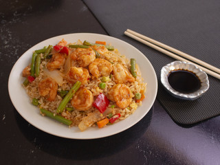 Shrimps with Rice and Vegetables Cantonese Style on a White Plate with Soy Sauce 