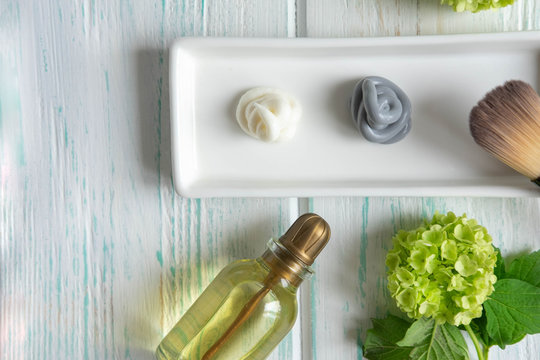 Face Mask, Scrub And Brush For Application With Flowers On A Wooden Background. SPA Concept. View From Above