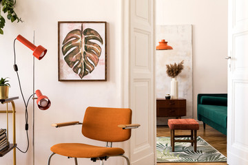 Stylish compositon of retro home interior with mock up poster frame, vintage orange chair, velvet sofa, design lamps, gold shelf, plants and elegant accessories. Nice home decor of living rooms. 