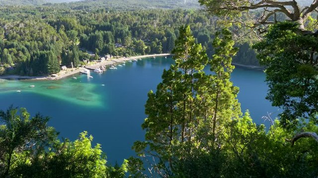 Looking between rich green pine trees at Villa La Angostura, Argentina. It is a town located on the northwest shore of the Nahuel Huapi Lake in Patagonia, Southern Andes. 4K