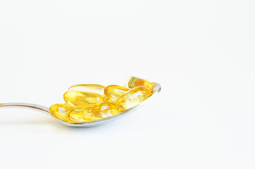  Omega 3 fish oil capsules in silver spoon on white background.  Concept of healthcare.  Copy space.
