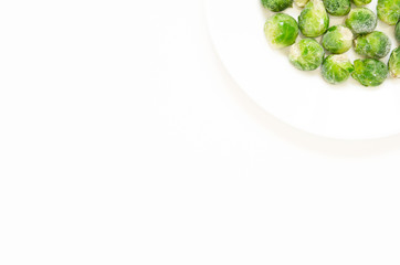 Frozen Brussels sprouts on a white plate. Top view, flat lay, copy space.