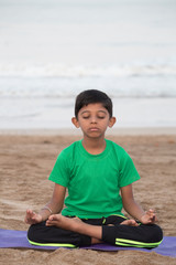 Fototapeta na wymiar Boy meditating early morning on the beach