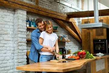 Lovely cheerful couple cooking dinner together and having fun at rustic kitchen