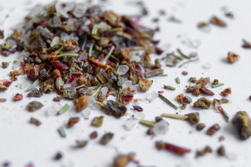 many different spices and salt scattered on a white background